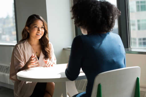 Image of two young professionals talking at a table