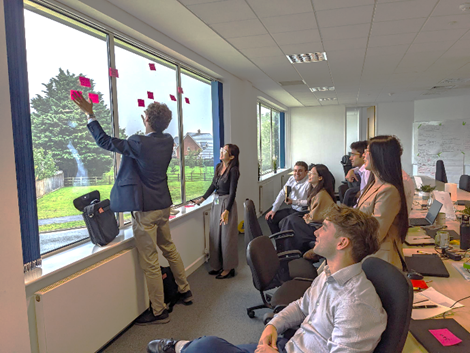 Image of people in an office looking at an array of post-it notes on the window